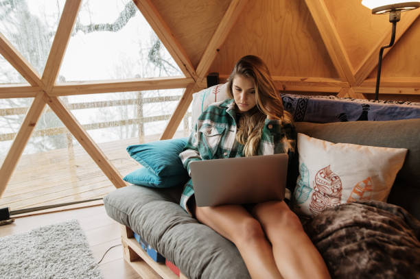 istock Young woman using laptop in a cozy wooden dome 1286377213