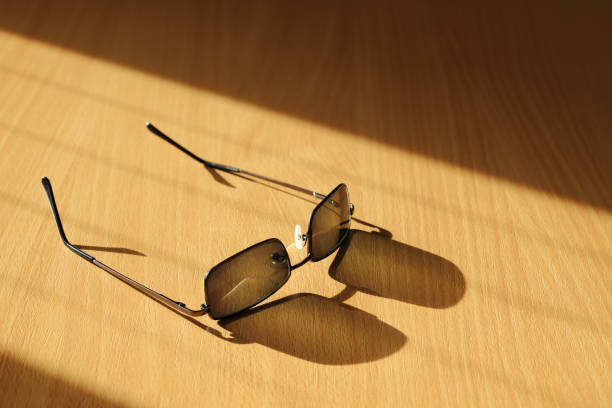istock Glasses with dark lenses on wooden table with their shadow 1286379627
