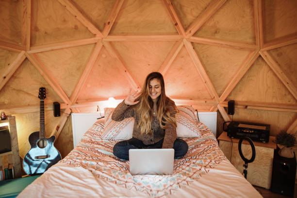 istock Young woman using laptop sitting on bed 1286380993