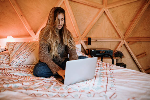 istock Young woman using laptop sitting on bed 1286380995
