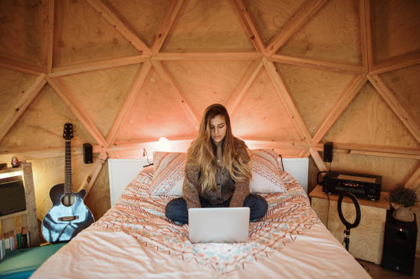 istock Young woman using laptop sitting on bed 1286381593
