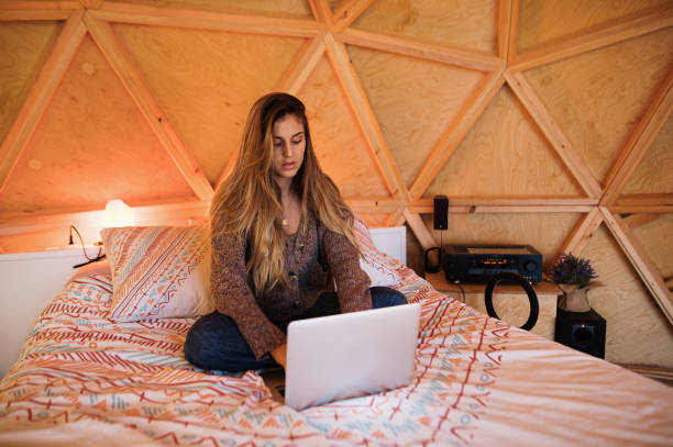 istock Young woman using laptop sitting on bed 1286381674