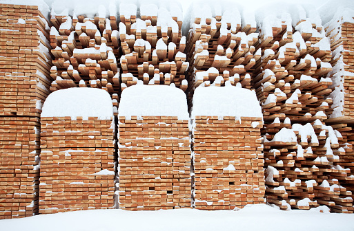 A lumber mill with piles of produced boards and construction material. Image taken in winter after fresh snow.