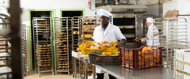 istock Positive african-american  bakery worker lays fresh bread 1286386420