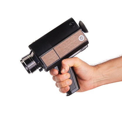 Cinematographer holding an old fashioned analog Super8, 8mm film movie camera on white background. Aiming the camera as a gun
