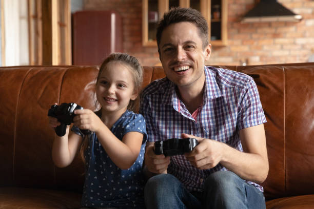 istock Smiling dad and small daughter play video games 1286390246