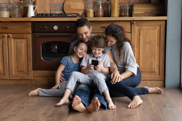 istock Happy parents with small kids use cellphone in kitchen 1286390265