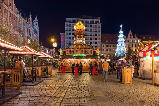 Wroclaw, Poland - December 9, 2019: Hut under Krasnal - a chalet with figures of dwarfs on Christmas market at Market Square in night. Krasnal or Krasnoludek is a Polish mythological type of gnome or dwarf, and a modern symbol of the city of Wroclaw. Unknown people walk around the market stalls.