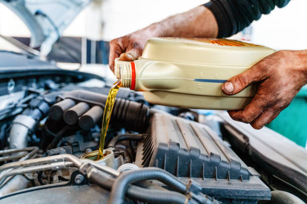 verter aceite al motor del coche. aceite de motor fresco vertido durante un cambio de aceite en un automóvil - motor oil bottle fotografías e imágenes de stock