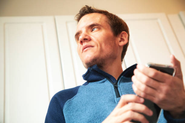 istock Mature autistic trans man looking away while using mobile phone in his kitchen 1286399919