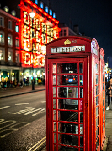 Two classic red telephone booth in front of an illuminated Christmas lights during night time in London, UK