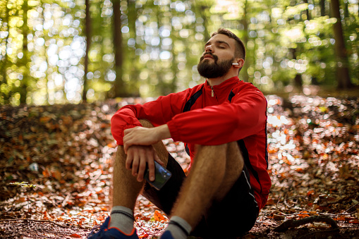 Retrato de joven relajado con auriculares bluetooth en el bosque photo