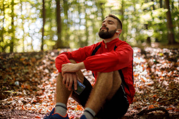 ritratto di giovane rilassato con cuffie bluetooth nella foresta - mental health foto e immagini stock