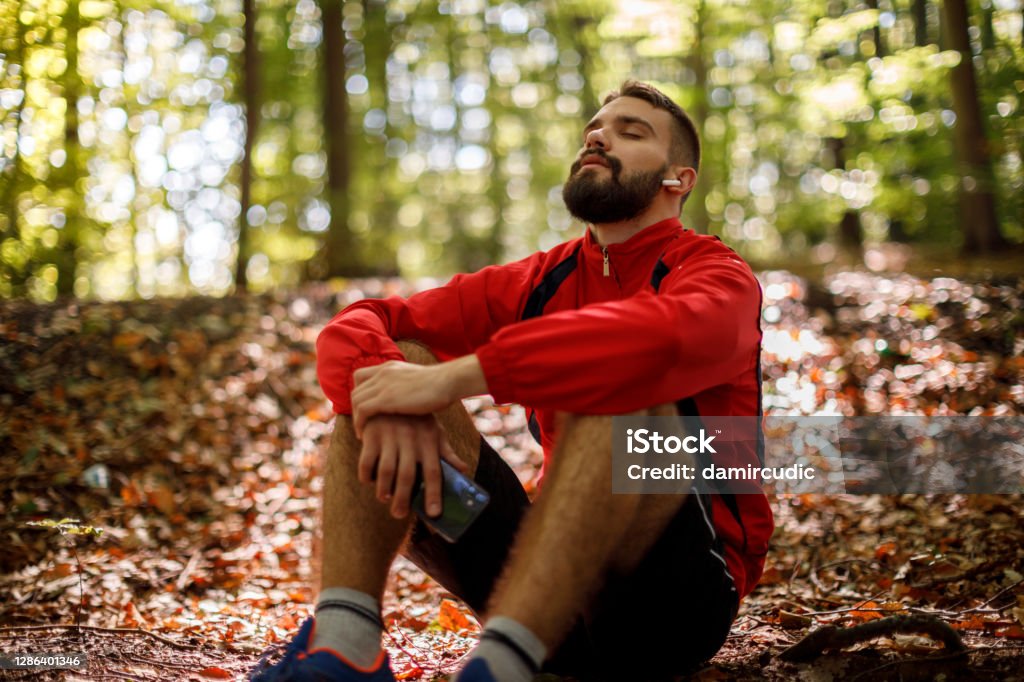 Portrait of relaxed young man with bluetooth headphones in forest Men Stock Photo