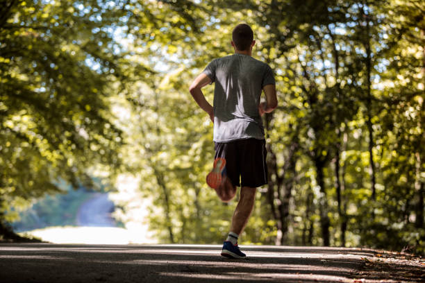 istock Rear view of young athletic man jogging in nature 1286401498
