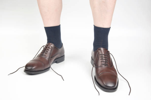 白い背景に靴下と茶色の古典的な革靴の男性の足 - ほどけた ストックフォトと画像