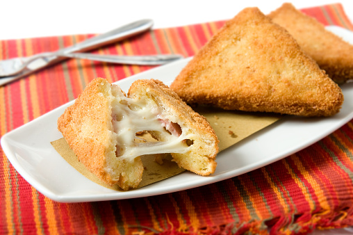 a typical dish of Roman cuisine in Italy called mozzarella in carrozza, bread in fried breadcrumbs and with stringy mozzarella on the bottom of a red placemat