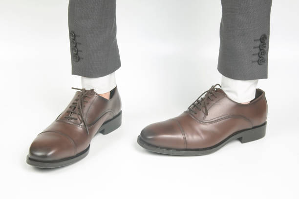 istock Classic brown leather shoes worn on the hands on a white background 1286404289