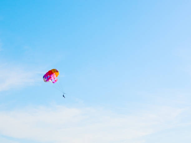 istock Man on multicolor parachute on zipline in blue sky 1286411461