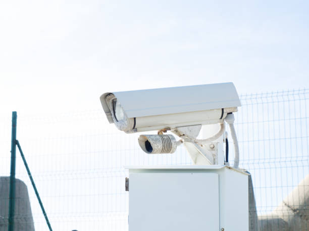 istock White surveillance camera on a stand outdoors behind a fence 1286411556