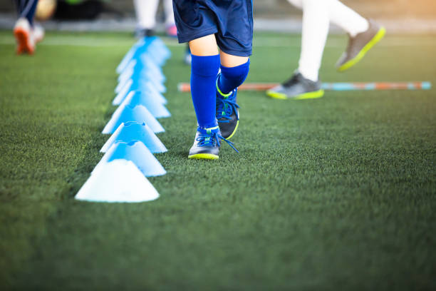 istock Selective focus to kid soccer players jogging beside cone marker on green artificial turf for training. 1286414191