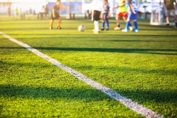 istock Selective focus to white lines on green artificial grass football fields with kid soccer player. 1286414208