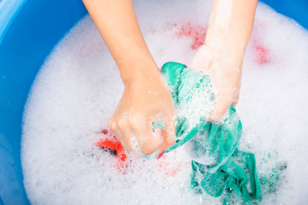 istock Woman use hands washing color clothes in basin 1286417718