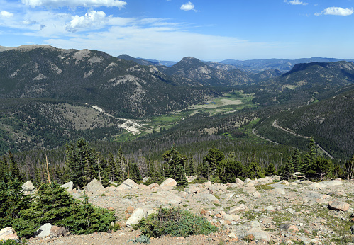 Green, Fall River Valley in the Rocky Mountain National Park on a beautiful, summer day. Climbing forested, mountain slopes, the Trail Ridge Road (US 34) is visible on the right.