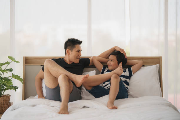 azjatycki tata i syn mają dobry czas na rozmowę na łóżku w domu. koncepcja relacji ojca i syna i dzień ojca - wyrzygać rodzinę zdjęcia i obrazy z banku zdjęć
