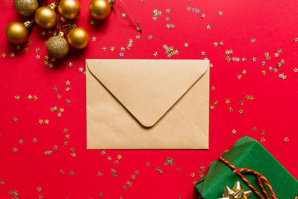 istock Christmas composition. Envelope, wrapped gift, toys on red background with golden confetti. new year concept. Greeting card, xmas celebration 2020. Flat lay, top view, copy space, mockup 1286428647