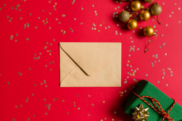 istock Christmas composition. Envelope, wrapped gift, toys on red background with golden confetti. new year concept. Greeting card, xmas celebration 2020. Flat lay, top view, copy space, mockup 1286428678