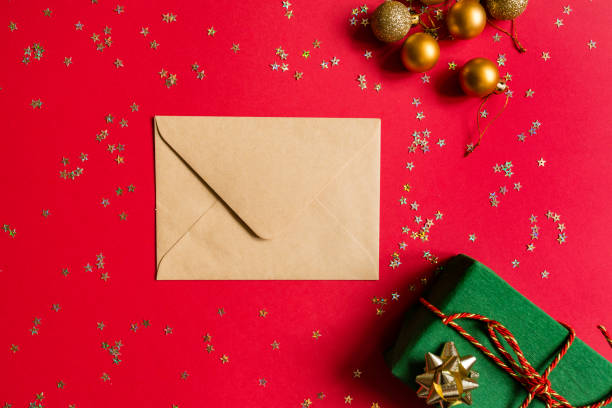 istock Christmas composition. Envelope, wrapped gift, toys on red background with golden confetti. new year concept. Greeting card, xmas celebration 2020. Flat lay, top view, copy space, mockup 1286428719