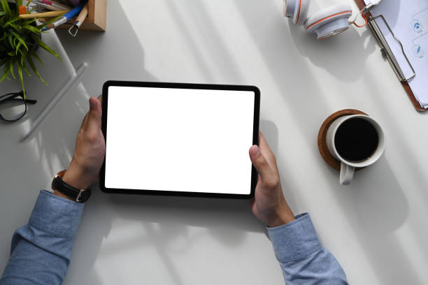 istock Top view of man sitting at work space and using tablet with white screen for advertising text. 1286431631
