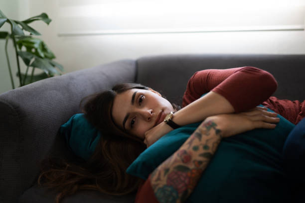 istock Depressed young woman making eye contact and hugging a pillow 1286432546