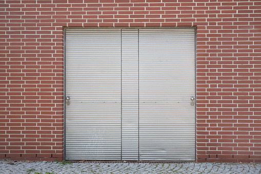 New brick wall and closed metal door, beautiful industrial background with space for text, horizontal format