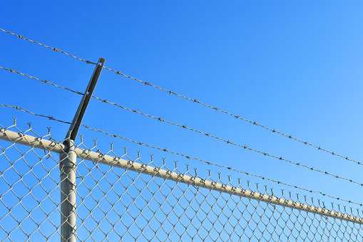 Security fence with barbed wire, unfocused background