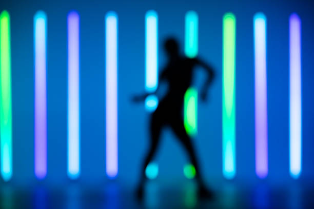 istock Blurred frame young hip-hop female dancer performing solo in the studio on a colorful background with neon lighting tube 1286446424