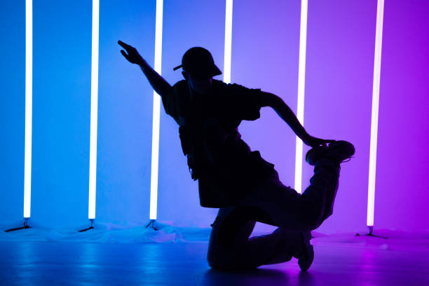 istock Young handsome man breakdancing with stylish clothes. Neon light tube background. Acrobatic bboy dancer. Breakdancing school poster. Close up 1286447080