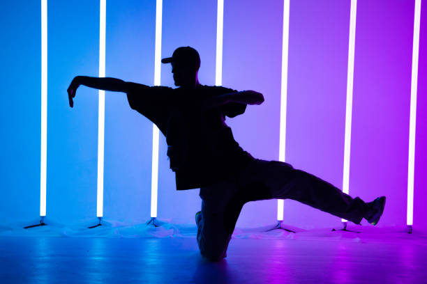istock Young handsome man breakdancing with stylish clothes. Neon light tube background. Acrobatic bboy dancer. Breakdancing school poster. Close up 1286447081