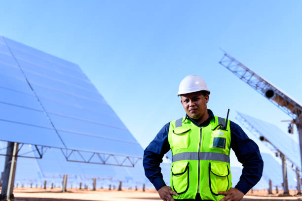 Solar power generation plant worker in front of heliostats A worker at  the Khi Solar One solar energy generation plant in the desert near Keimoes in the Northern Cape, South Africa in front of heliostats reflecting heat to a generating tower. heliostat photos stock pictures, royalty-free photos & images