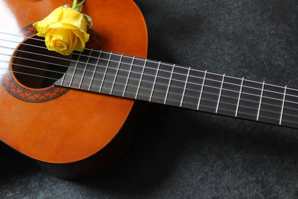 istock Light acoustic guitar and yellow rose. Beautiful romantic background 1286453217