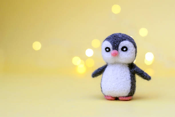 istock Toy wool penguin on a yellow background with bokeh 1286455161
