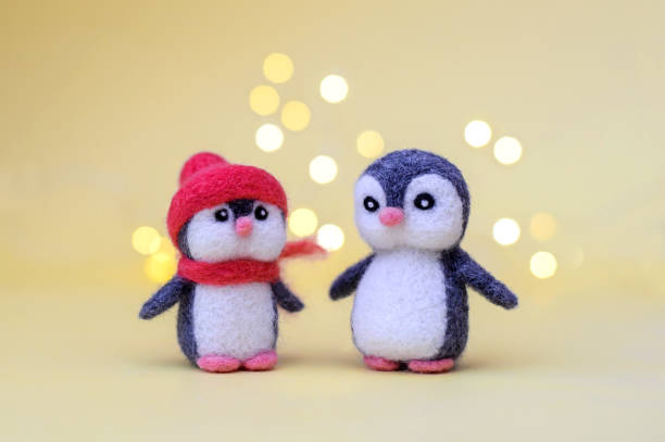 istock Two woolly toy penguins on a yellow background with bokeh 1286455169