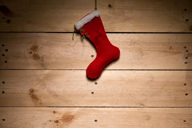 Christmas decoration - Red felt boot in front of a wooden wall and Christmas motifs