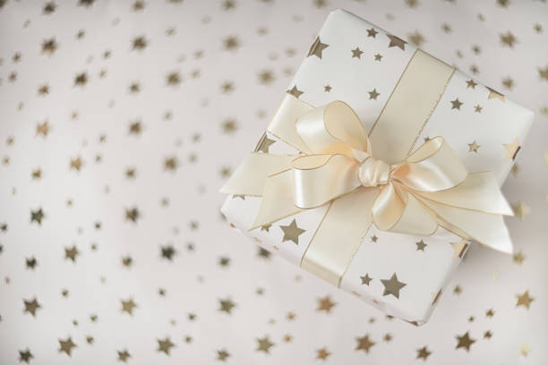 istock Gift box with beige bow on a light background with stars. Flat lay with soft focus. 1286459137