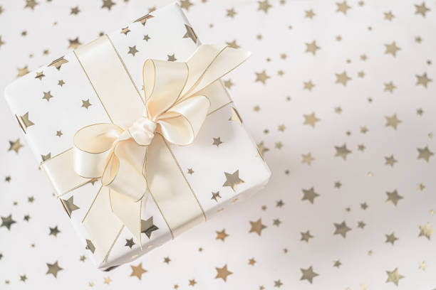 istock Gift box with beige bow on a light background with stars. Flat lay with soft focus. 1286459152