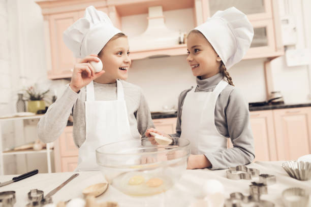 istock Children in kitchen. Brother is showing sister how he is going to break egg. 1286461636