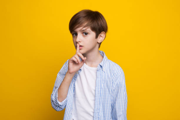 istock Young caucasian boy is gesturing the silence soung posing serious on a yellow studio wall in casual clothes 1286461889