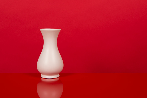 Empty white vase, on a red design interior