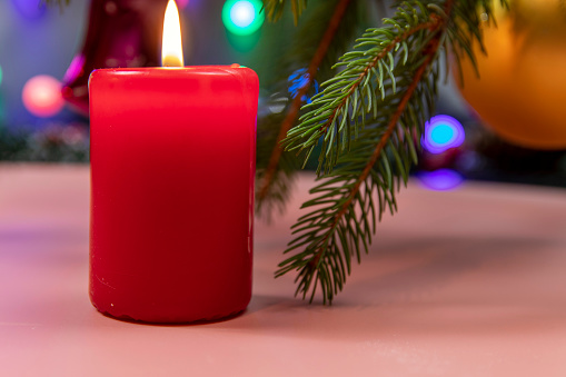 Christmas candle and festive décor on a dark background. Holiday concept for Christmas and New Year. Christmas decoration with a burning candle on the table. Selective focus.